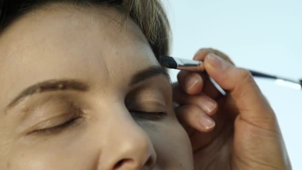 Eye makeup woman applying eyeshadow powder. Stylist is doing make up for female by eyeliner — Stock Video