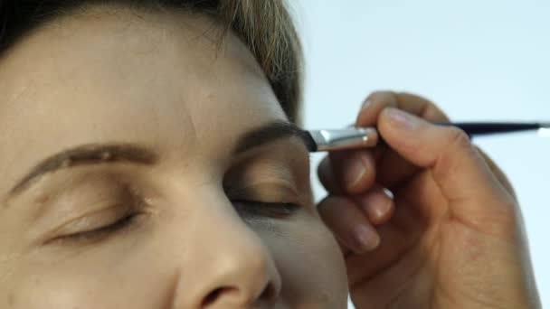 Maquillaje de ojos mujer aplicando sombra de ojos en polvo. Estilista está haciendo maquillaje para hembra por delineador de ojos — Vídeo de stock