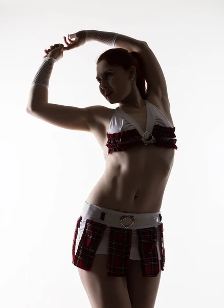 Jonge sexy striptease danseres in een minirok tegen een lichte achtergrond — Stockfoto