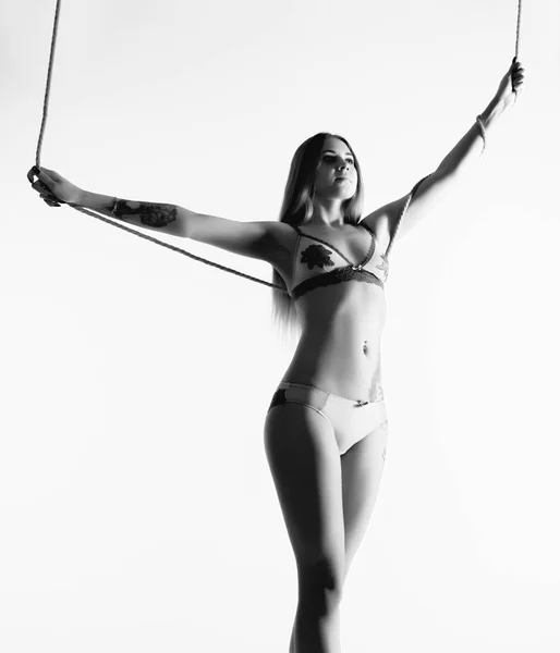 Menina fina perfeita com uma corda posando em um fundo claro. Corpo atlético sexy. preto e branco — Fotografia de Stock