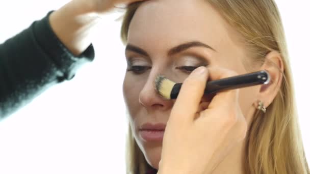 Primer plano del maquillador profesional que hace el maquillaje diario, pone polvo en las mejillas de las mujeres con cepillo — Vídeos de Stock