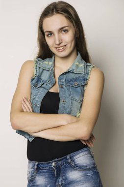 neşeli gülümseyen hippi kız bir kot ceket ve hafif bir arka plan üzerinde poz şort