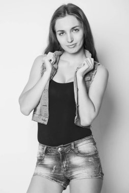 genç güzel mutlu şık hippi kız bir kot ceket ve hafif bir arka plan üzerinde poz şort. siyah ve beyaz