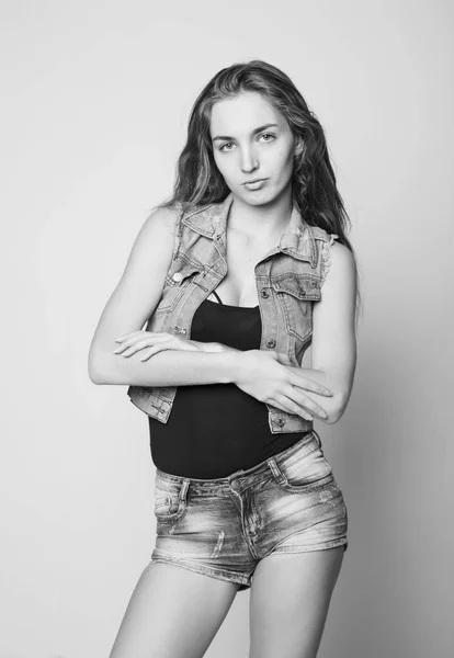 Young beautiful happy stylish hipster girl in a denim jacket and shorts posing on a light background. black and white — Stock Photo, Image