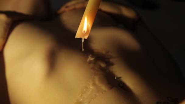 Vax från ett ljus droppar på en naken kropp. par i ett intimans ögonblick — Stockvideo