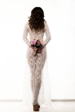 hipster gelin buketi beyaz bir arka plan üzerinde tutan beyaz şeffaf elbise giymiş. çiçekli kız gelin veya bahar sabahında