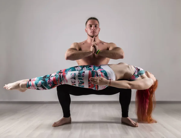 Sport muž a žena, která dělá acroyoga cvičení v šedém pozadí — Stock fotografie