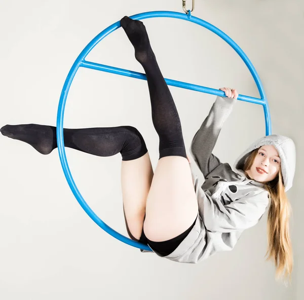 Joven acróbata en el aire anillo gimnasia. Mujer colgando en anillo aéreo sobre un fondo blanco — Foto de Stock