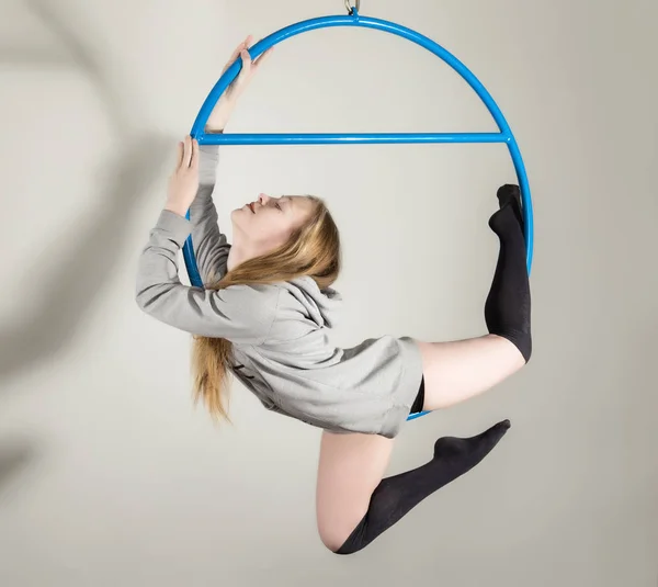 Joven acróbata en el aire anillo gimnasia. Mujer colgando en anillo aéreo sobre un fondo blanco — Foto de Stock