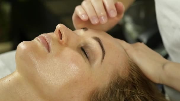 Mulher bonita recebendo massagem facial no spa. cuidados com a pele facial no salão de beleza. câmara lenta — Vídeo de Stock