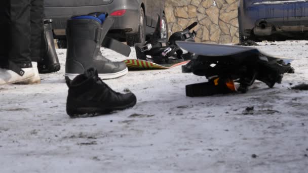 El hombre se pone zapatos para snowboard cerca del coche en un aparcamiento de montaña — Vídeos de Stock