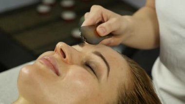 Güzel kadın kazıyıcı guaş bir yüzle bir acupressure var. Çin alternatif tıp