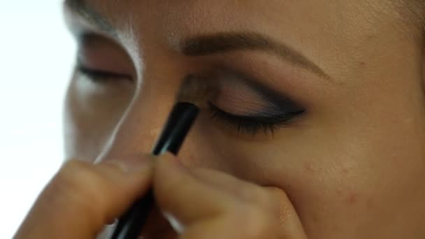 Mulher maquiagem olho aplicando pó sombra. Stylist está fazendo maquiagem para a fêmea por eyeliner — Vídeo de Stock