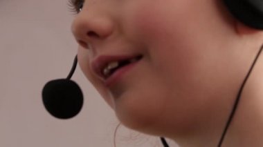 Kulaklık bir mikrofon şarkı, sevimli küçük bir kız closeup. 4k