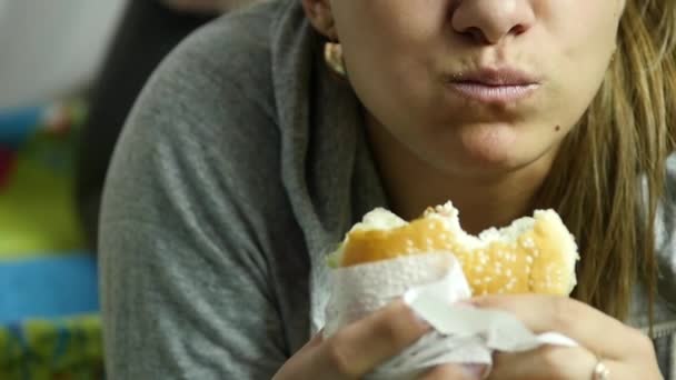 Mujer gorda sosteniendo hamburguesa de comida rápida y masticándola. comiendo comida chatarra. Movimiento lento — Vídeos de Stock