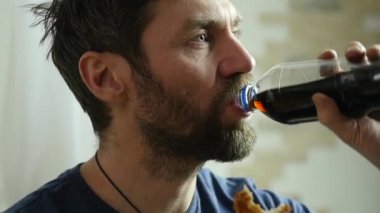 adam fast food, tavuk nuggets ve gazlı bir içecek ile kanatları yiyor. çok abur cubur. ağır çekim