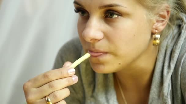 Женщина питается нездоровой пищей с большим удовольствием. Девушка ест картошку фри. замедленное движение — стоковое видео