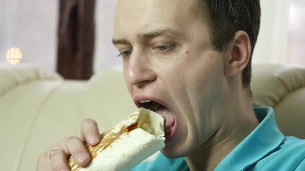 Hubený muž jí rychlé občerstvení snack s velkou radosti. Guy žvýkání nezdravé jídlo s velkou chutí. Zpomalený pohyb — Stock video