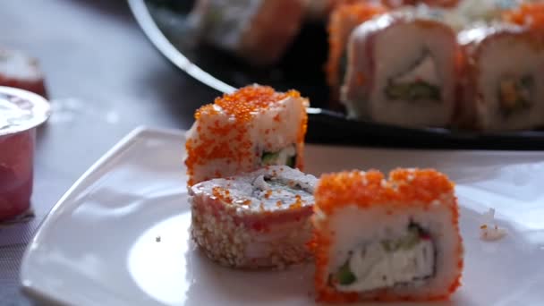 Mujer comiendo sushi en el restaurante cocina japonesa, utiliza palillos. primer plano rollos cámara lenta — Vídeo de stock