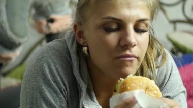 memnun kadın yatak odasında lokanta hamburger yeme. çok abur cubur. Ağır çekim