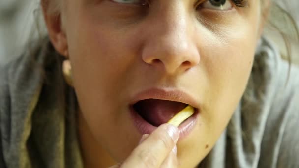 Jonge vrouw eet Franse frietjes. snel en junkfood concept. Slow motion — Stockvideo