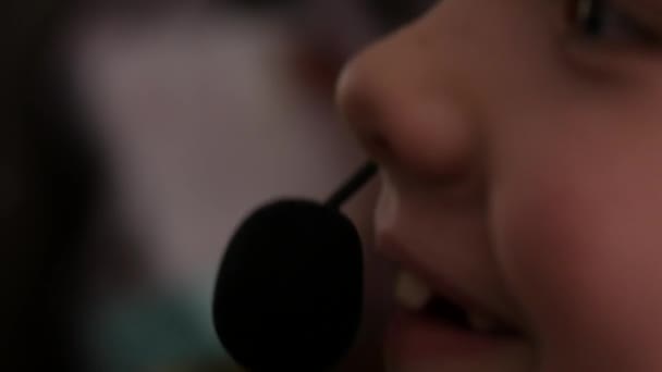 Gros plan d'une jolie petite fille en casque chantant dans un microphone. 4K — Video