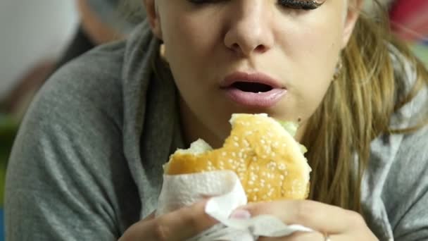 Mujer gorda sosteniendo hamburguesa de comida rápida y masticándola. comiendo comida chatarra. Movimiento lento — Vídeo de stock