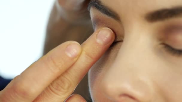 Visagist geldt een corrector onder zijn ogen, make-up voor mooie vrouw in de beauty salon — Stockvideo