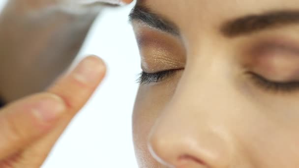 Artista de maquiagem aplica um corretor sob seus olhos, maquiagem para mulher bonita no salão de beleza — Vídeo de Stock