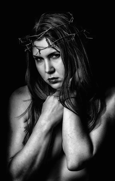 Sexy belle femme avec une couronne de fil de fer barbelé sur la tête sur un fond sombre. noir et blanc — Photo