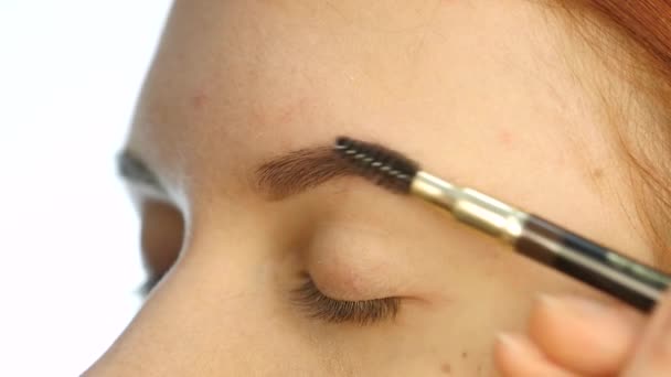 Close-up make-up artiesten handen met behulp van de borstel te schilderen wenkbrauwen voor een mooie client. Slow motion — Stockvideo