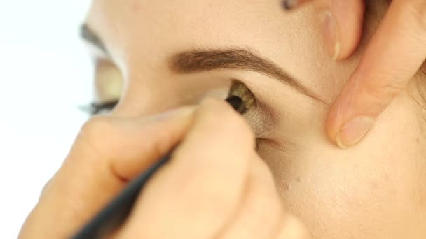 Рука макияжа крупным планом, нанося тени на женский глаз кистью. замедленное движение — стоковое видео