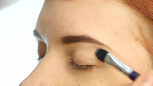Yakın çekim makyaj sanatçı el, göz farı fırçası kullanarak kadının gözle uygulamak. ağır çekim — Stok video