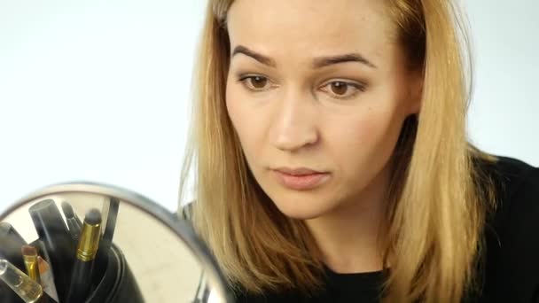 Vacker kvinna gör vardagsmakeup och hålla makeup borste framme av spegel. slowmotion — Stockvideo