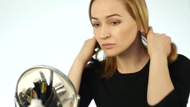 Jeune femme blonde debout devant le miroir à la maison et corrigeant ses cheveux. au ralenti — Video