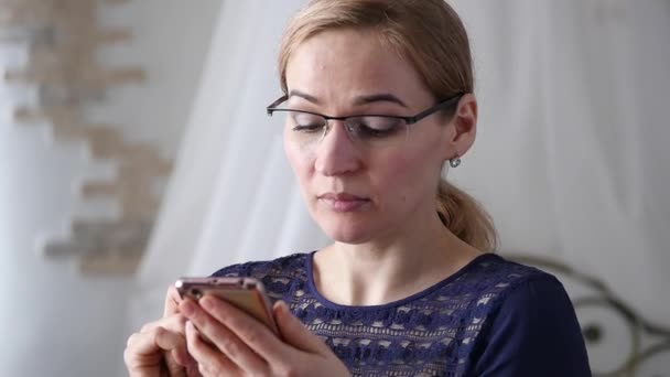 Mujer de negocios rubia en gafas comprobando algo en el teléfono inteligente. cámara lenta — Vídeos de Stock