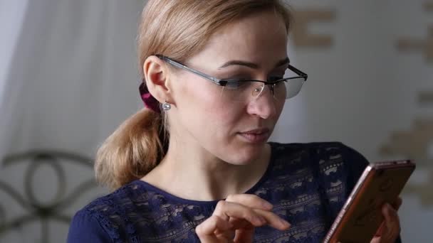 Blonde Geschäftsfrau mit Brille checkt etwas auf dem Smartphone. Zeitlupe — Stockvideo