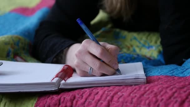 Sed jonge vrouw ligt op bed en schrijft in haar dagboek. Adolescent ervaringen. Slow motion — Stockvideo