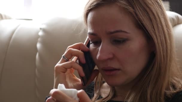 若い女性は、スマート フォンで誰かと話している間、悲しいと泣いているを感じる。4 k — ストック動画
