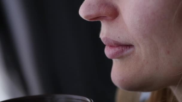 Ung kvinna dricker kaffe eller te nära fönstret. slowmotion — Stockvideo