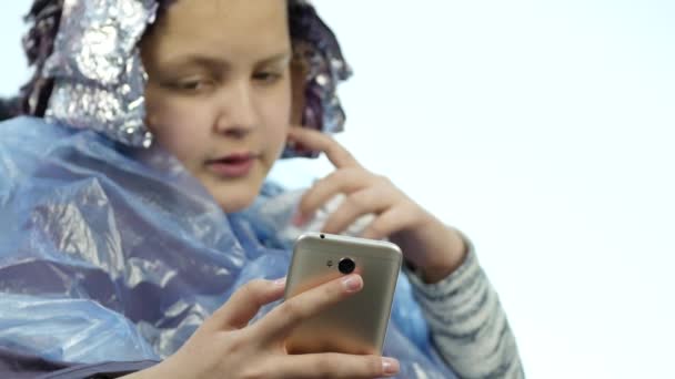 Meisje praten over een telefoon terwijl Kapper maakt kapsel, kleurstof voor een tiener in een schoonheidssalon. 4k — Stockvideo