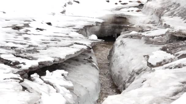 Pequeño río fluye a través del hielo en primavera. 4K — Vídeos de Stock