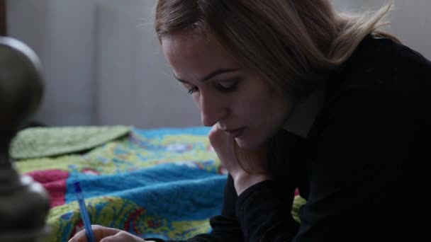 Pensiva casnică întinsă pe un pat și scriind în jurnalul ei. 4K — Videoclip de stoc