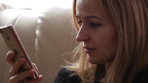 Молодая женщина пьет кофе или чай и разговаривает по телефону. 4K — стоковое видео