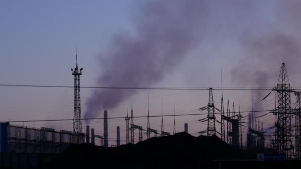 Air pollution from industrial plants. Pipes throwing black smoke on a evening sky. hanging wires and electric supports — Stock Video