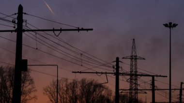 Yüksek gerilim elektrik Kulesi, siyah duman fabrika ve akşam gökyüzünde uçakta izi. 4k