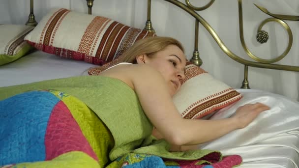 Blonde woman wakes up, looks at alarm clock and hides it under the pillow. slow motion — Stock Video