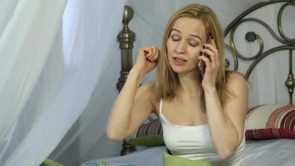 Emotiva bella donna bionda canta al telefono in un letto. 4K — Video Stock