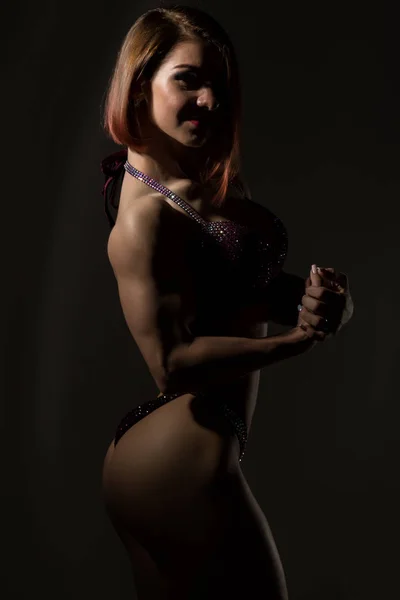 Attraktive Fitness-Frau, muskulöse junge Athletin auf dunklem Hintergrund — Stockfoto