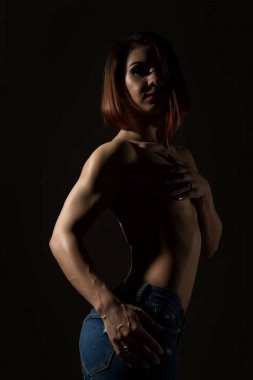 Genç kadın modeli ile kas vücut üzerinde karanlık bir arka plan teşkil etmektedir.